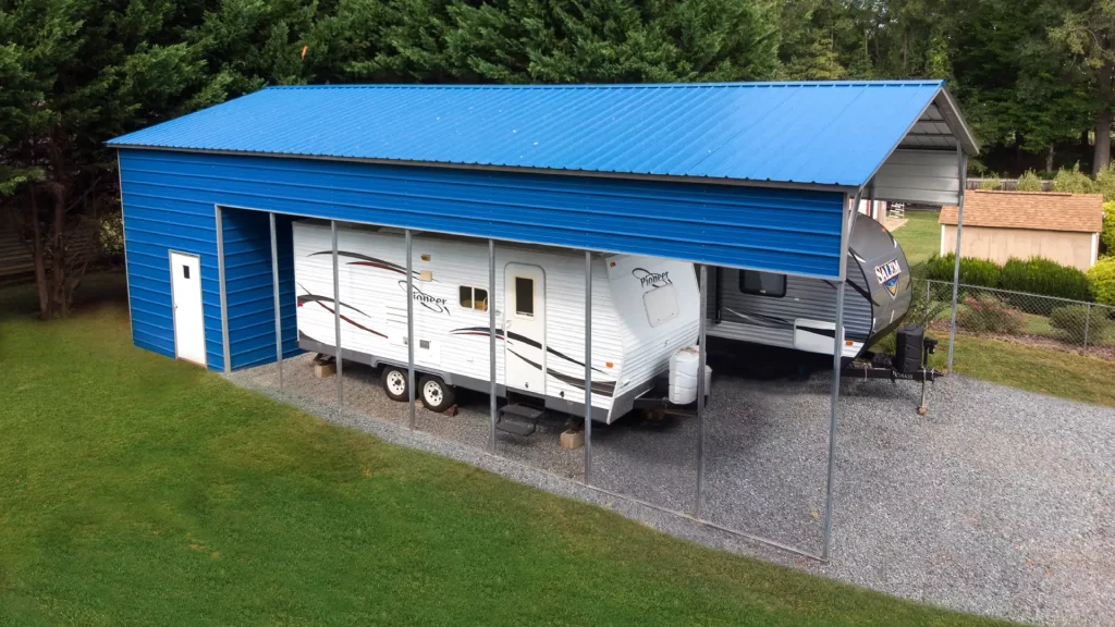 A metal building with a blue roof is housing a RV.