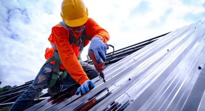 A construction worker is working on a metal building.