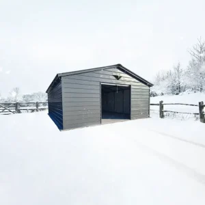 A 24X30X8 Vertical Roof Metal Garage in the snow with a fence in the background.