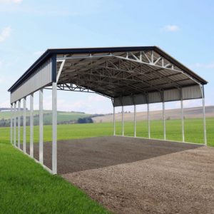 The 42X40X14/11 Vertical Roof Barn with a 12' wide lean-to features a gable roof design, standing proudly on a grassy field under the clear sky, exuding both utility and charm in its serene setting.