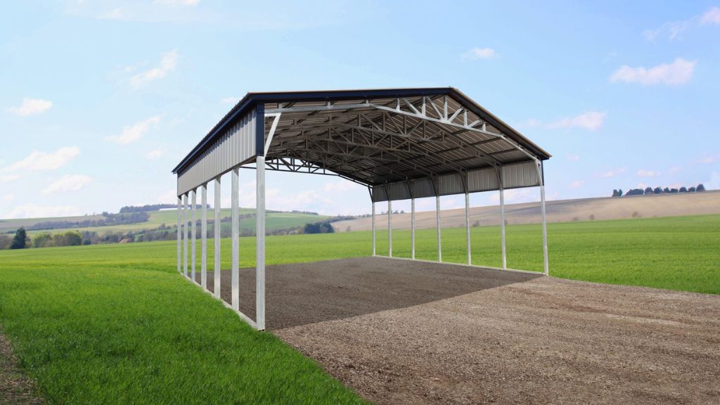 The 42X40X14/11 Vertical Roof Barn with a 12' wide lean-to features a gable roof design, standing proudly on a grassy field under the clear sky, exuding both utility and charm in its serene setting.