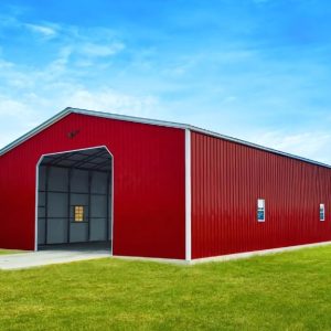 A large red metal barn, echoing the 40x60x12 Vertical Roof Commercial Metal Building, stands proudly on a green grassy field under a clear blue sky.